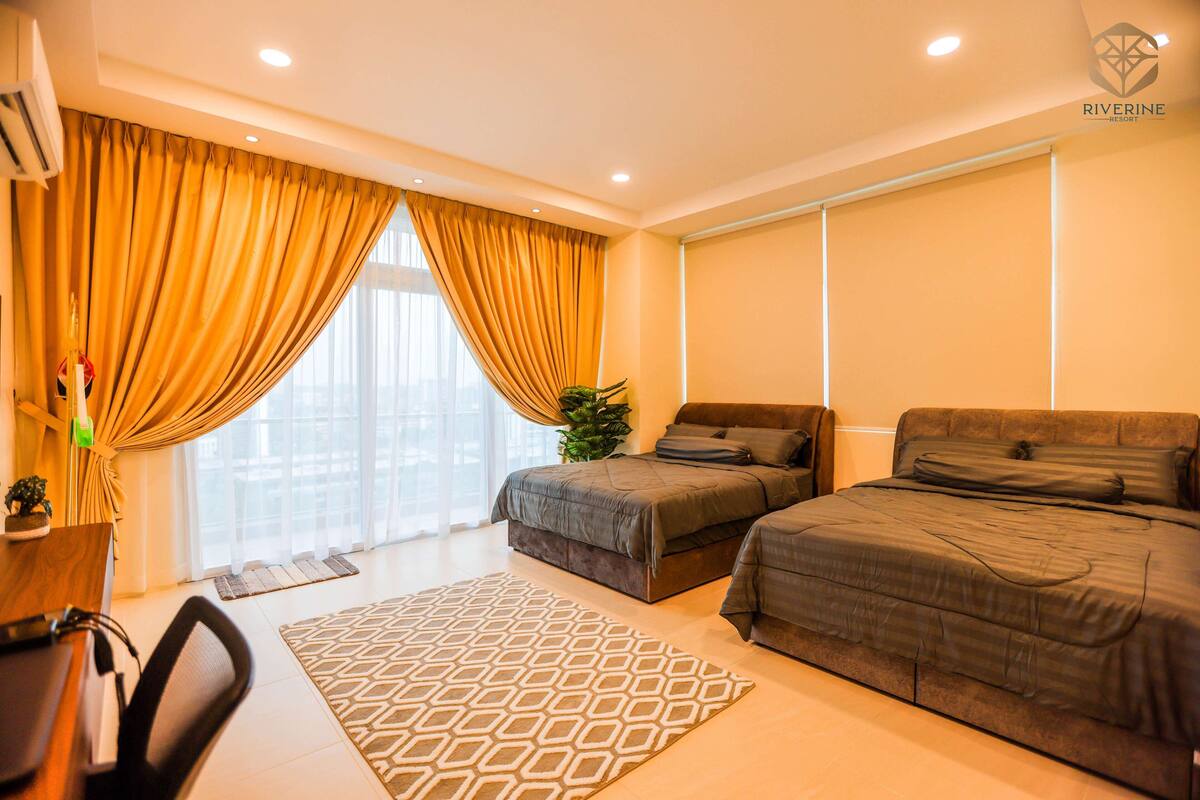 A modern hotel room with a large bed, a smaller bed, a desk, and a large window with curtains.