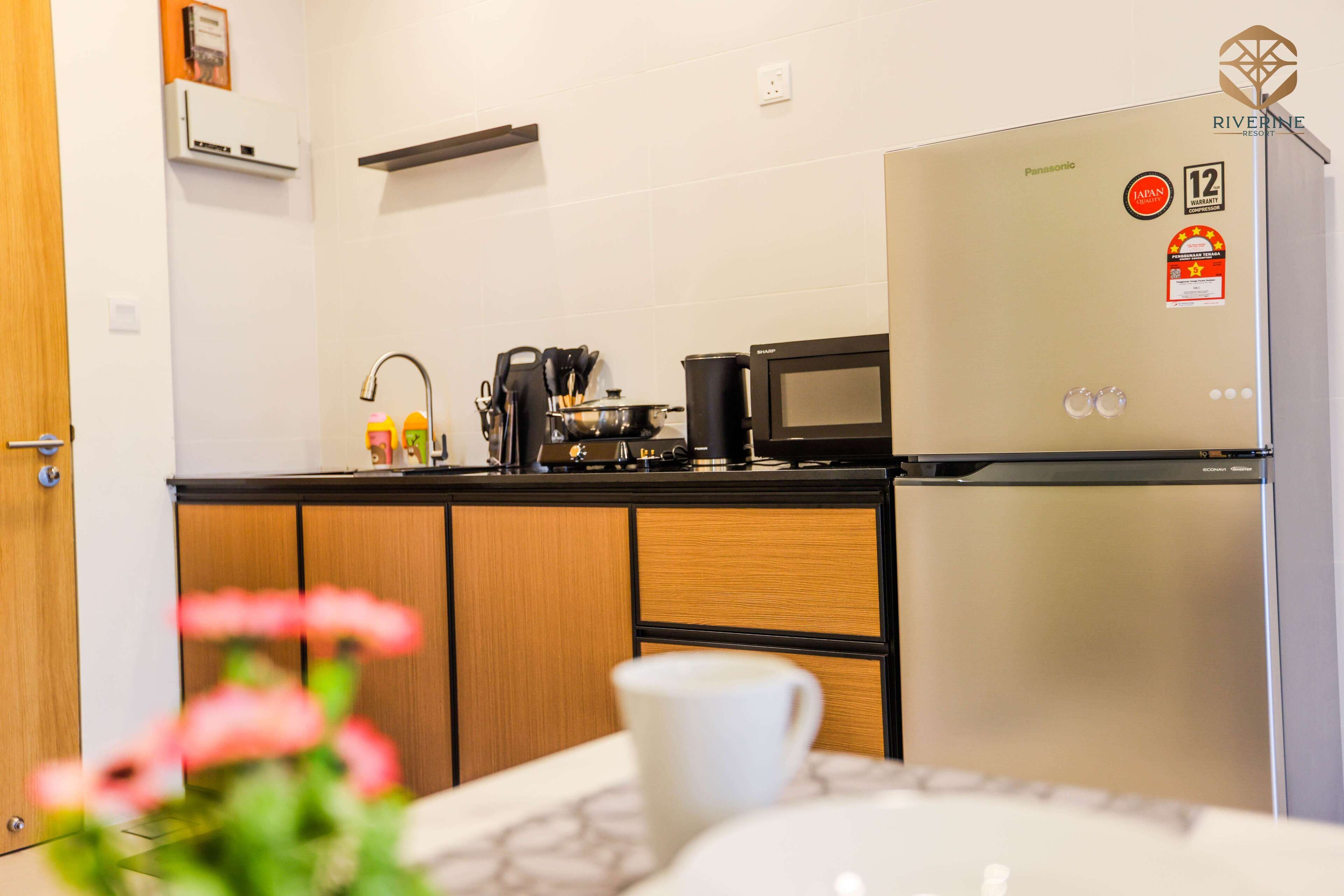 A modern kitchen with a refrigerator, microwave, and stove.