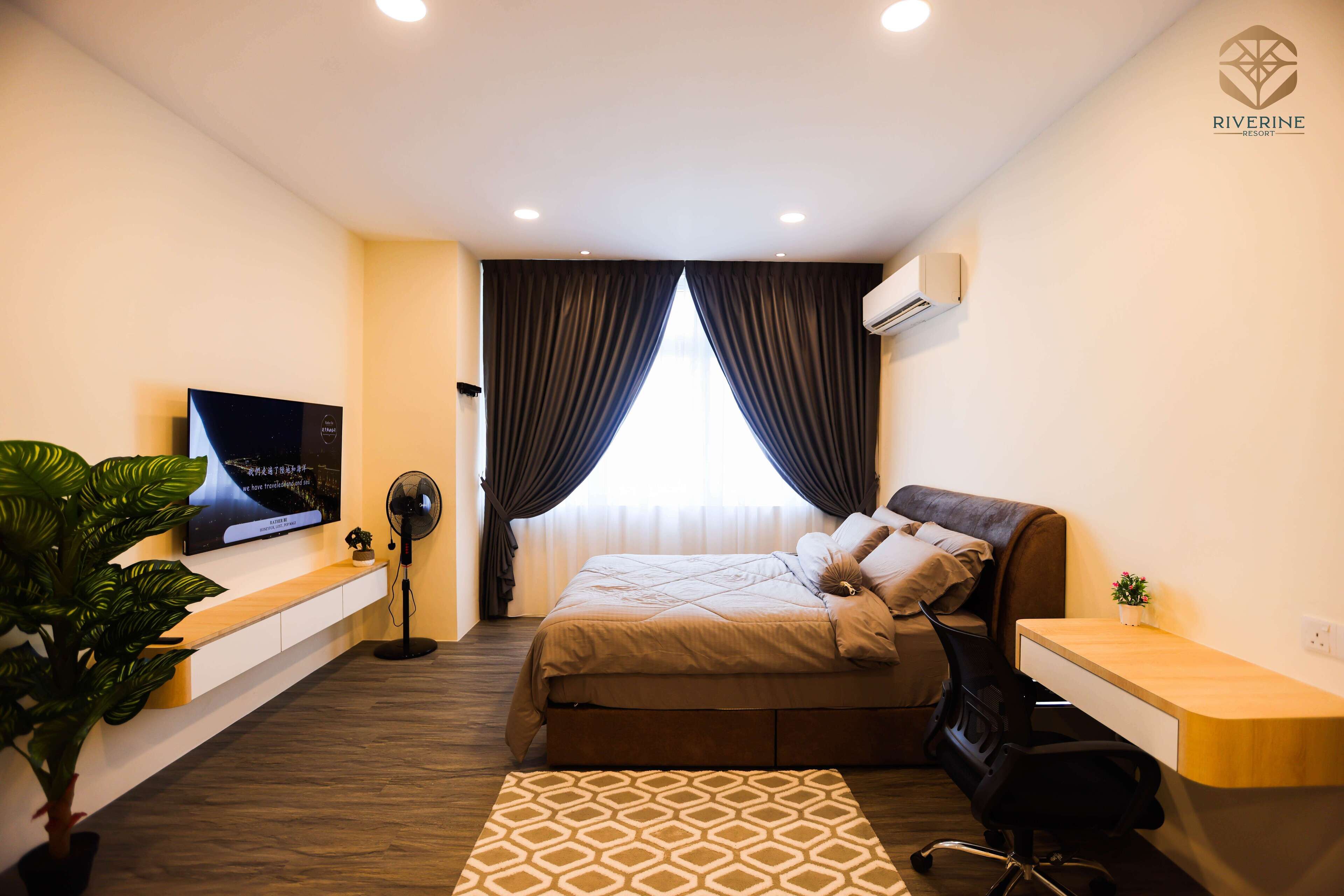A modern hotel room with a bed, a desk, a TV, and a plant.