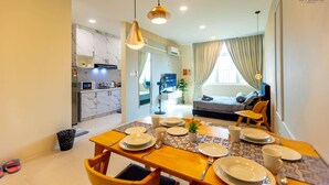 A modern hotel room with a dining area, kitchenette, and a living space with a sofa and TV. - Kuching Riverine Resort  (Kuching)