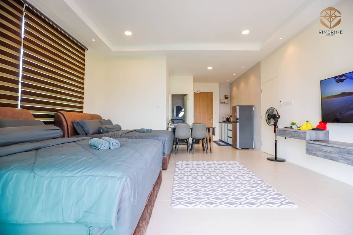 A modern hotel room with a large bed, a desk, and a dining area.