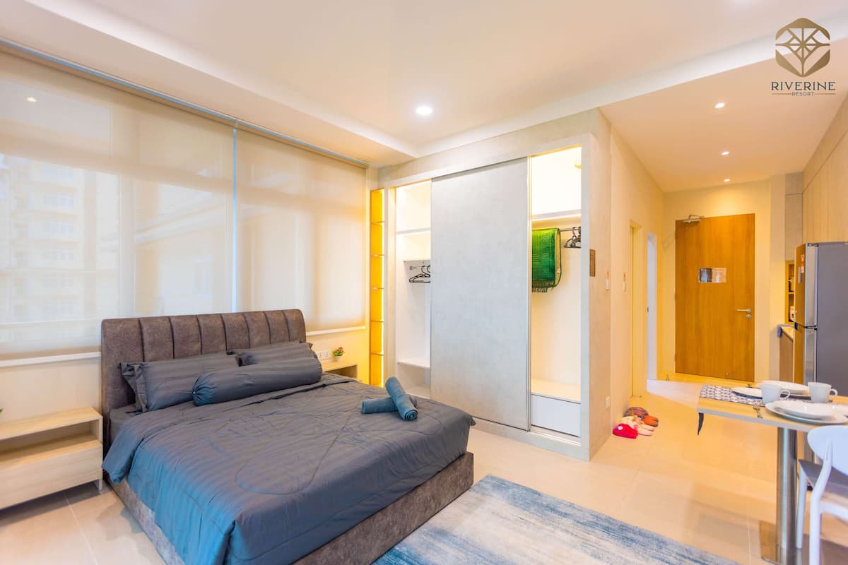 A modern hotel room with a large bed, a desk, and a view of the city.