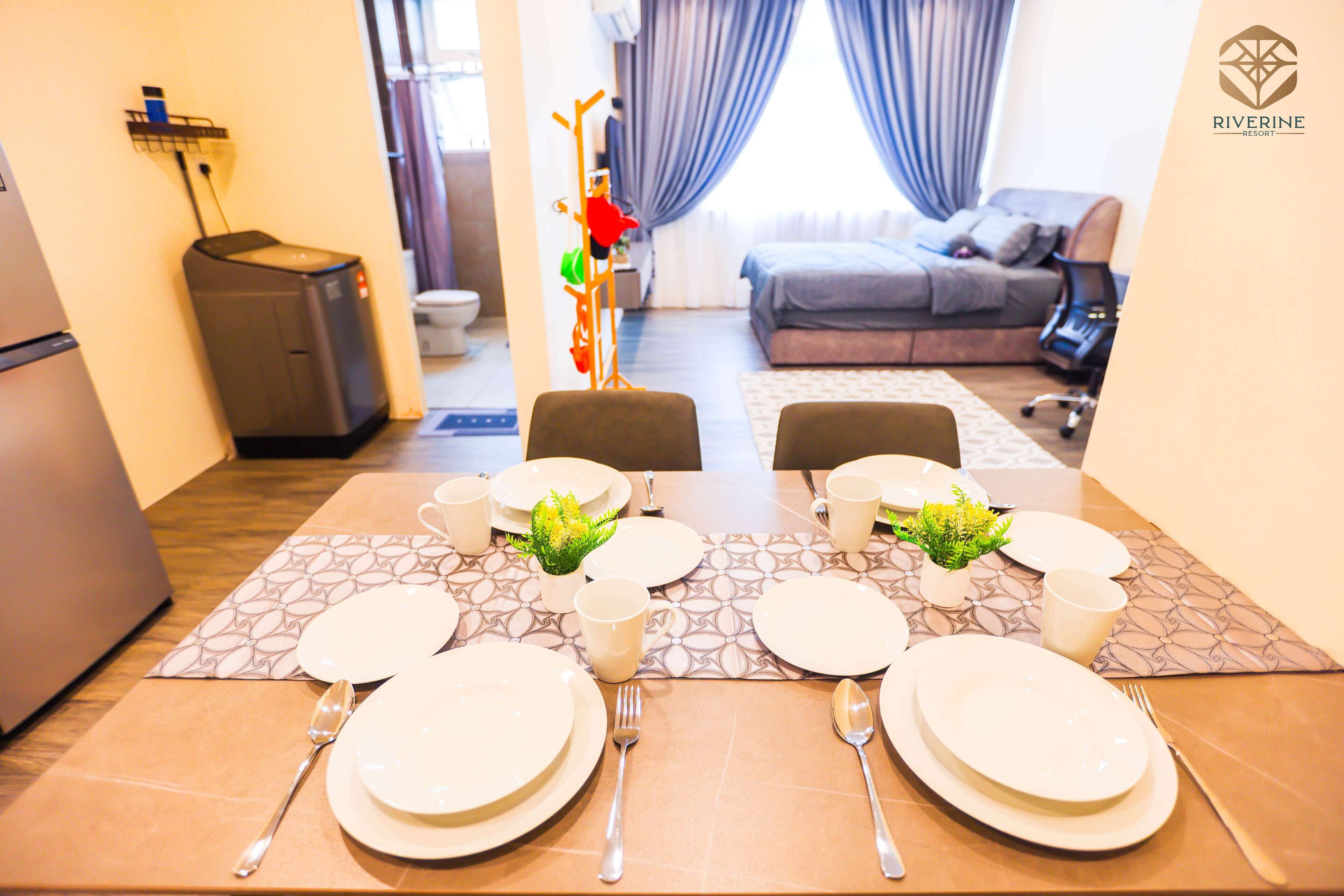 A dining area with a table set for four, a sofa, and a bed in the background.