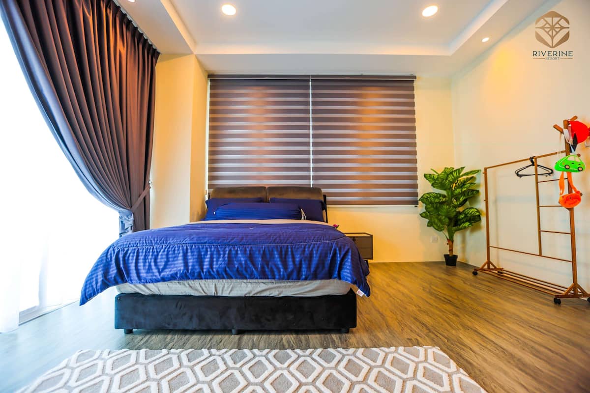 A bedroom with a bed, a potted plant, and a clothing rack.