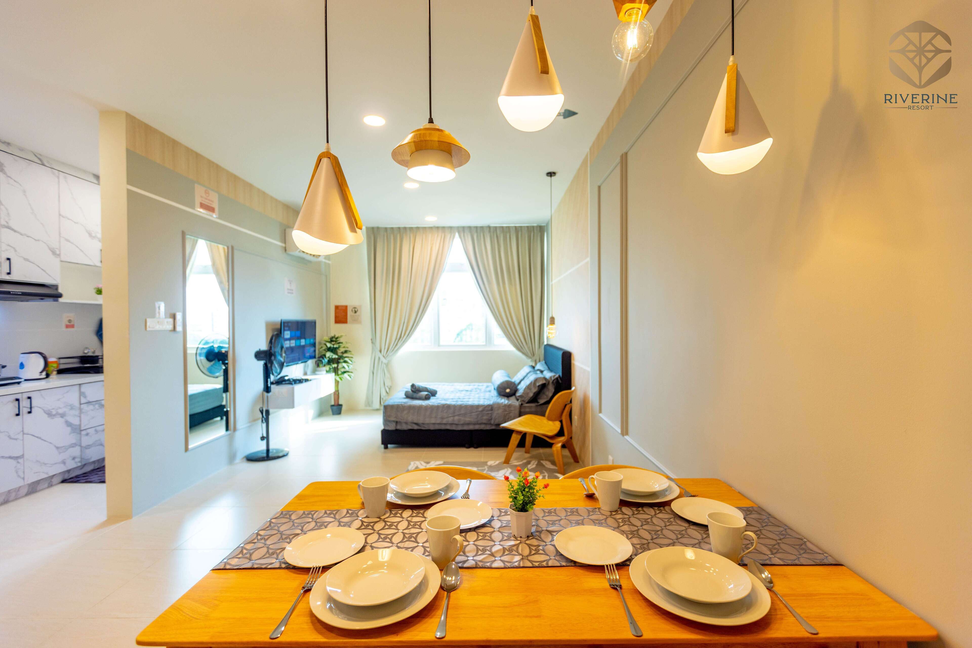Un comedor con una mesa preparada para cuatro, una cocina al fondo y una cama con vistas.