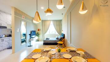 Un comedor con una mesa preparada para cuatro, una cocina al fondo y una cama con vistas.
