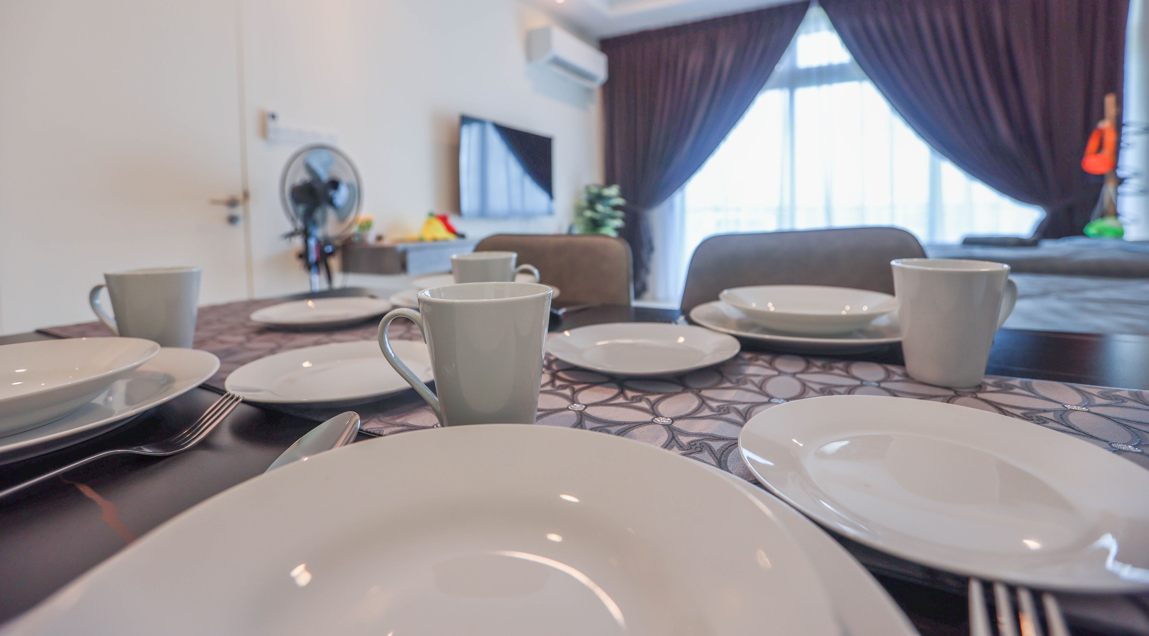 Una mesa de comedor con platos, tazas y cubiertos en una habitación de hotel.