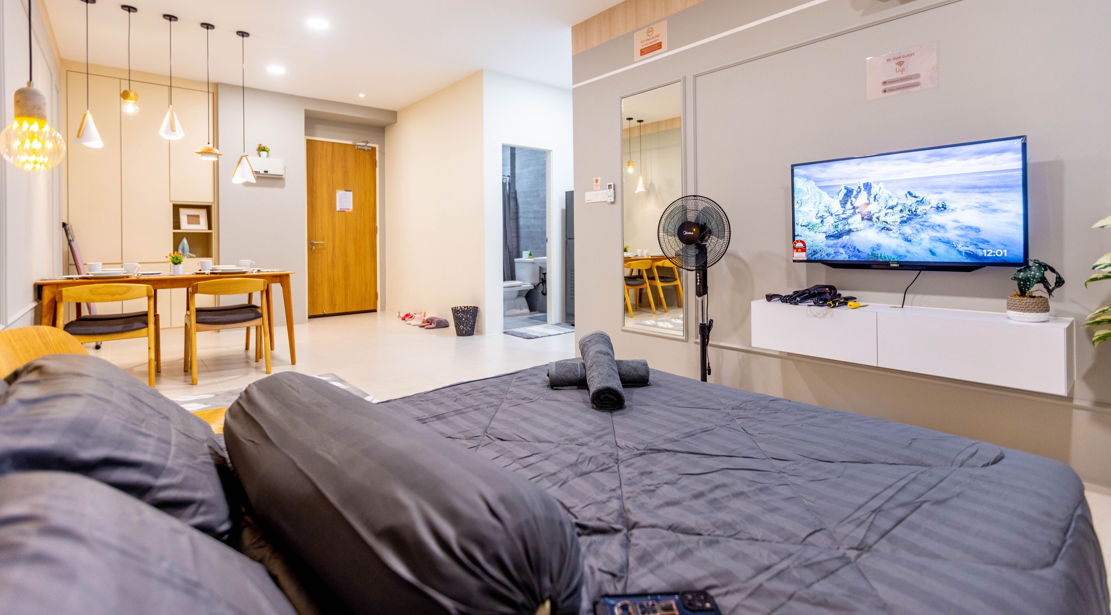 Ein modernes Hotelzimmer mit Bett, Schreibtisch, Stuhl, Fernseher und Ventilator.