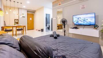 Ein modernes Hotelzimmer mit Bett, Schreibtisch, Stuhl, Fernseher und Ventilator.