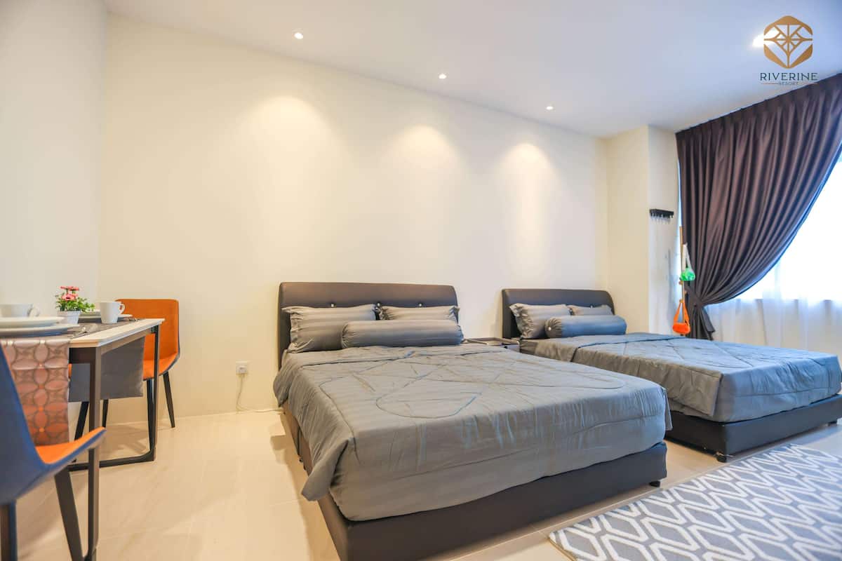 A hotel room with two beds, a desk with a chair, and a dining table.