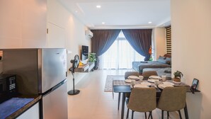 A modern hotel room with a kitchenette, a dining area, a sofa, and a large window with curtains. - Kuching Riverine Resort  (Kuching)