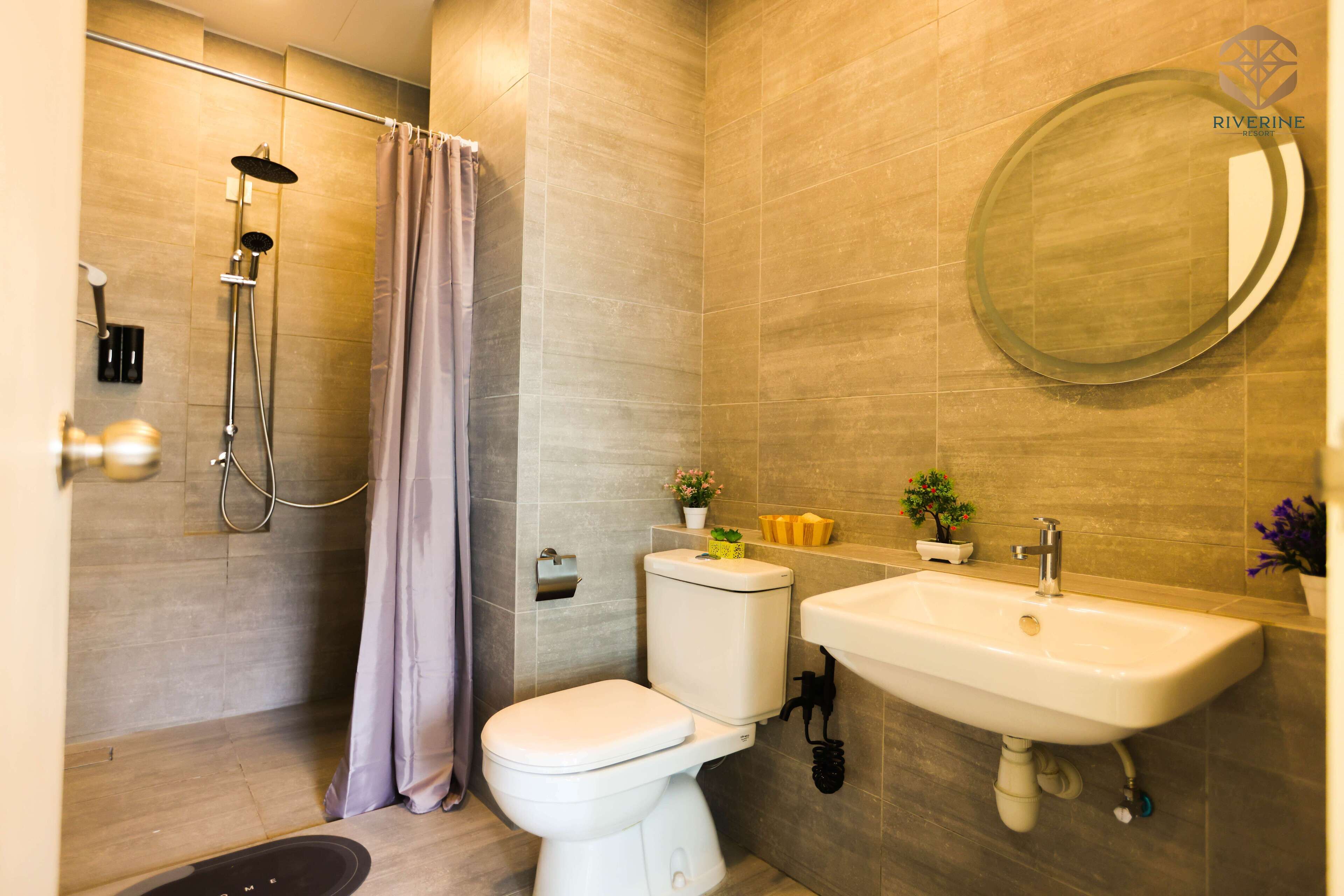 Ein modernes Badezimmer mit Dusche, Toilette, Waschbecken und einem runden Spiegel.