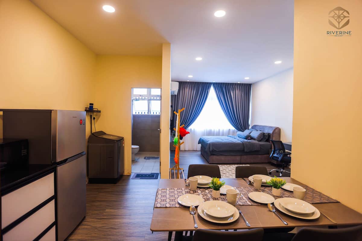 A compact hotel room with a dining area, kitchenette, and a bed.