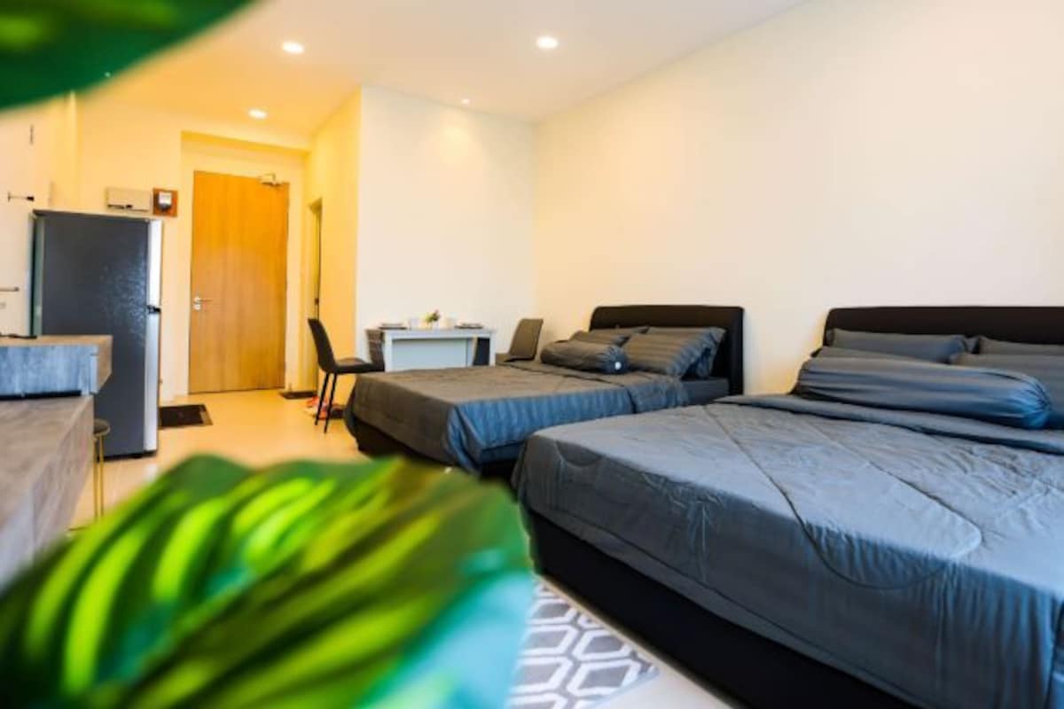 A hotel room with two beds, a desk, a chair, and a refrigerator.
