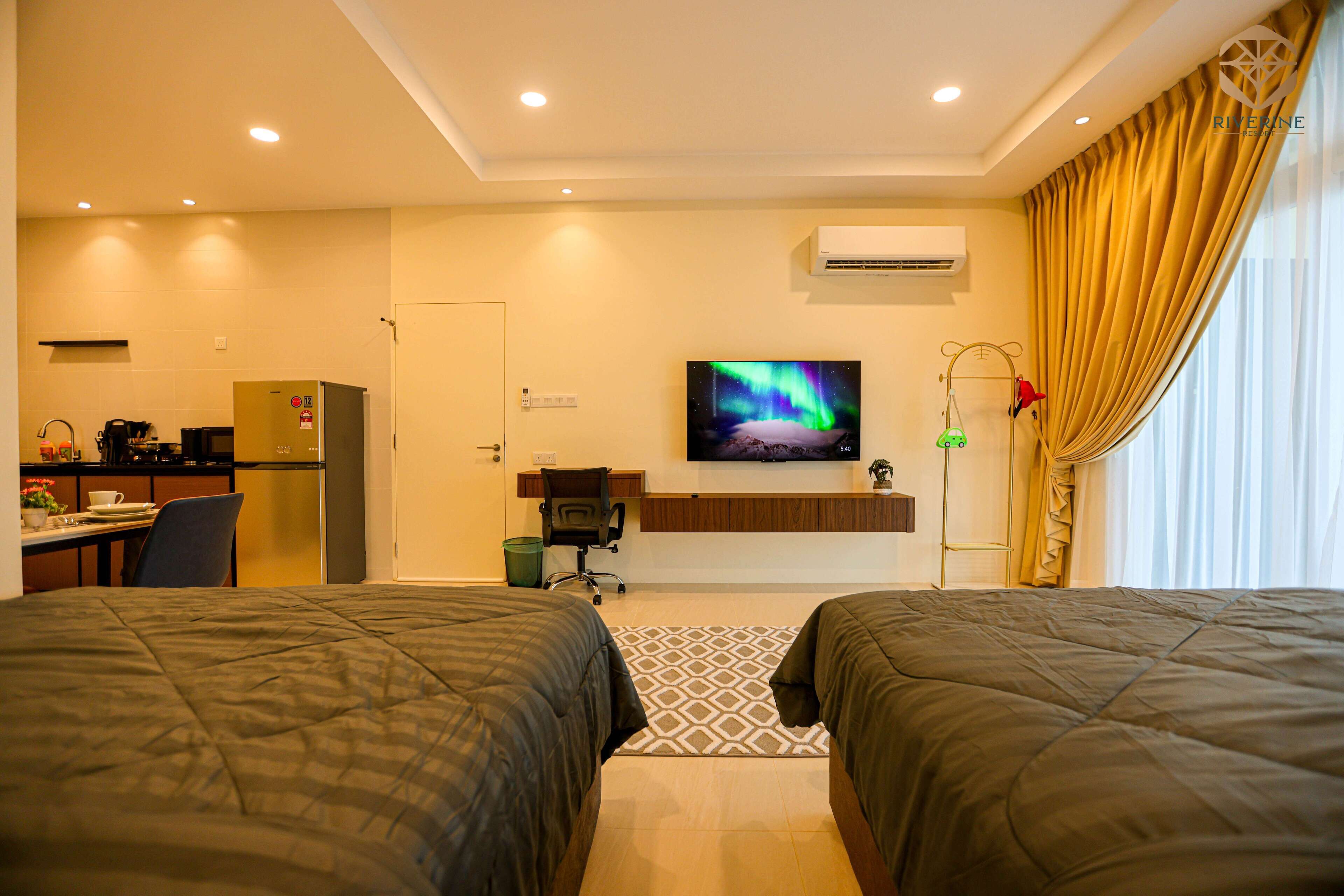A hotel room with two beds, a TV, a desk with a chair, a refrigerator, and a window with curtains.