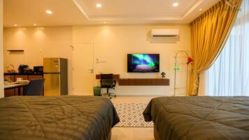 A hotel room with two beds, a TV, a desk with a chair, a refrigerator, and a window with curtains.
