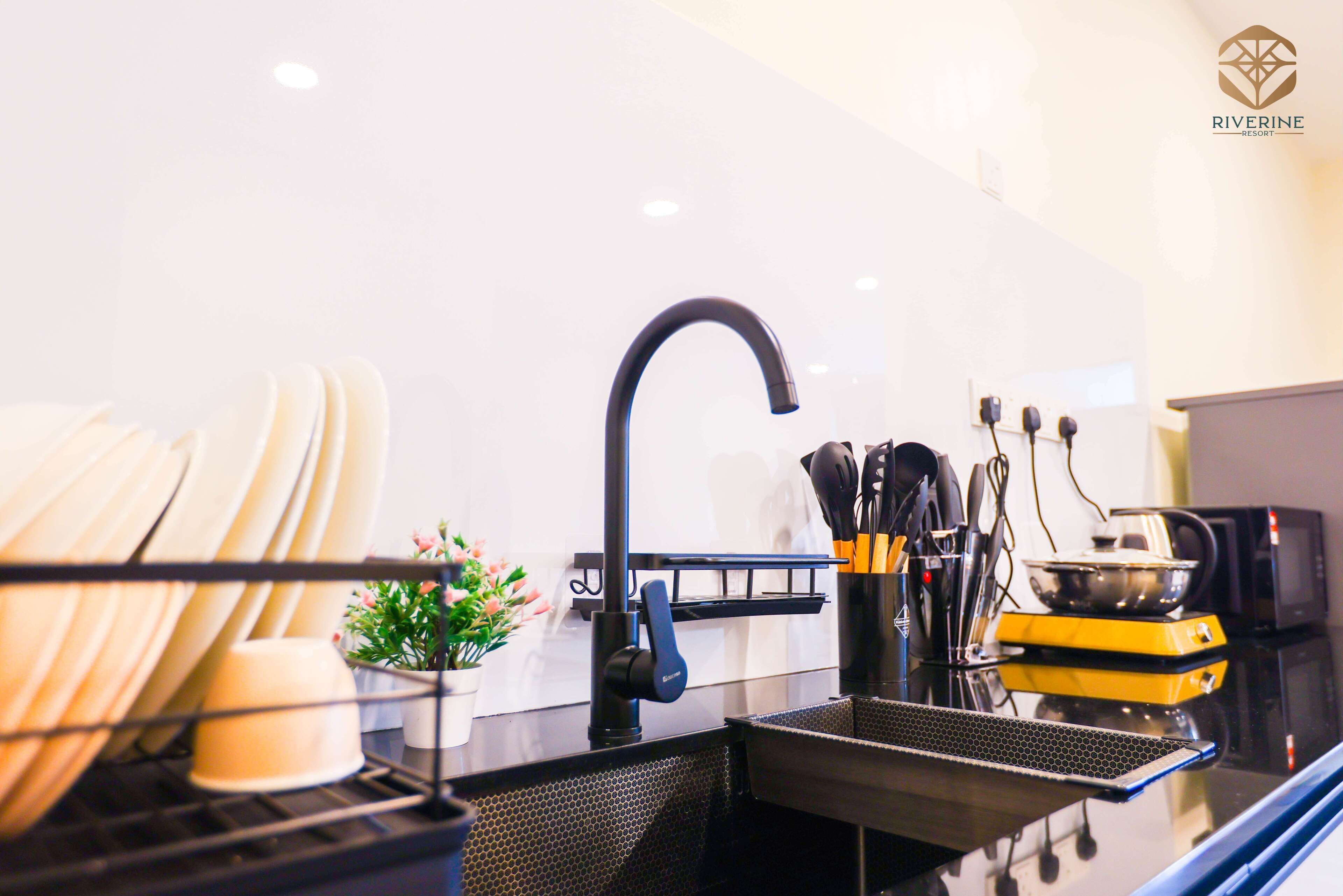A modern kitchen with a black faucet, a dish rack, and a yellow appliance.
