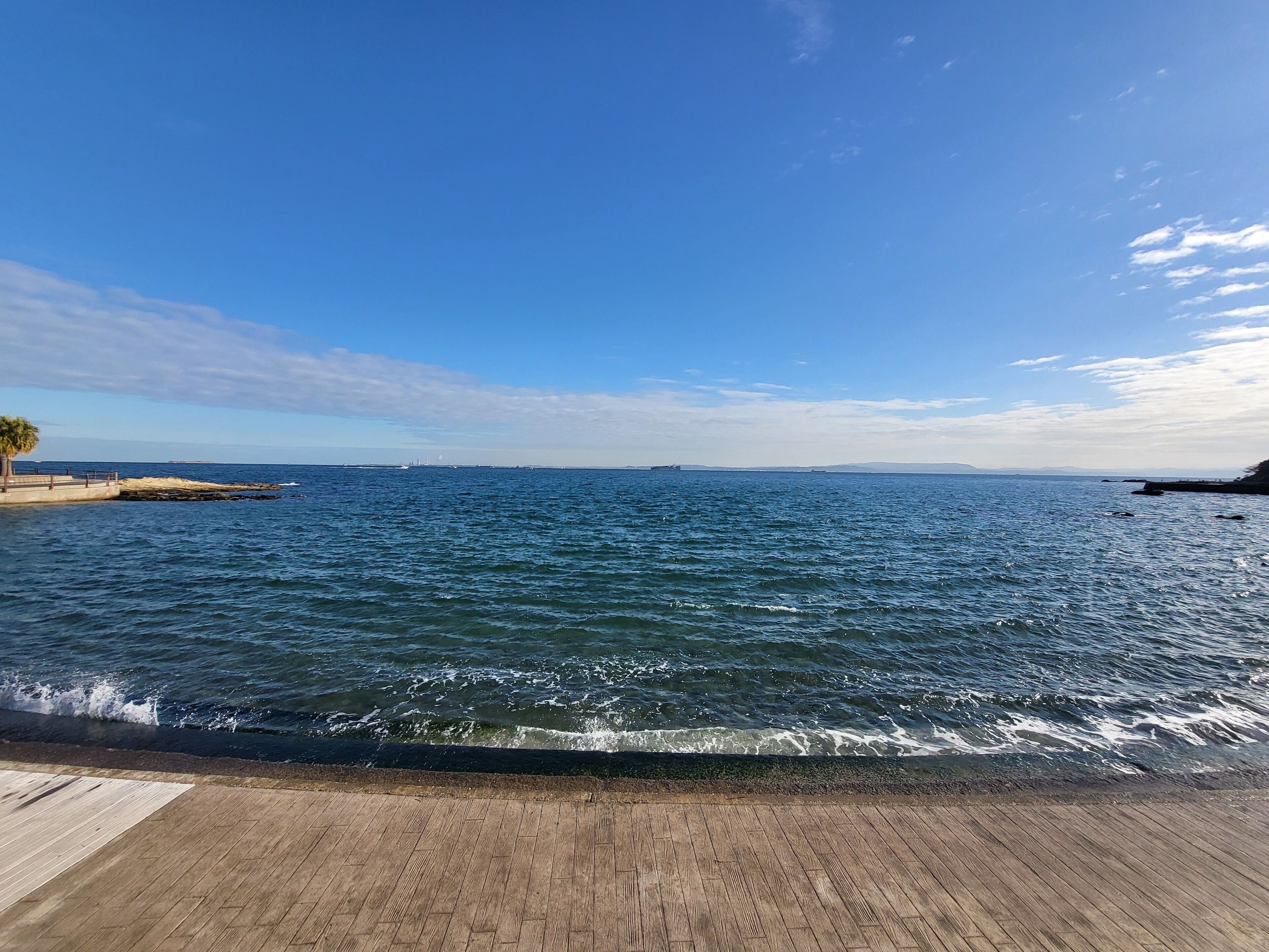 Una terraza de madera con vistas al mar tranquilo y un cielo despejado.