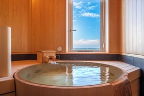 Een houten sauna met een groot raam, een houten bank en een waterfontein.