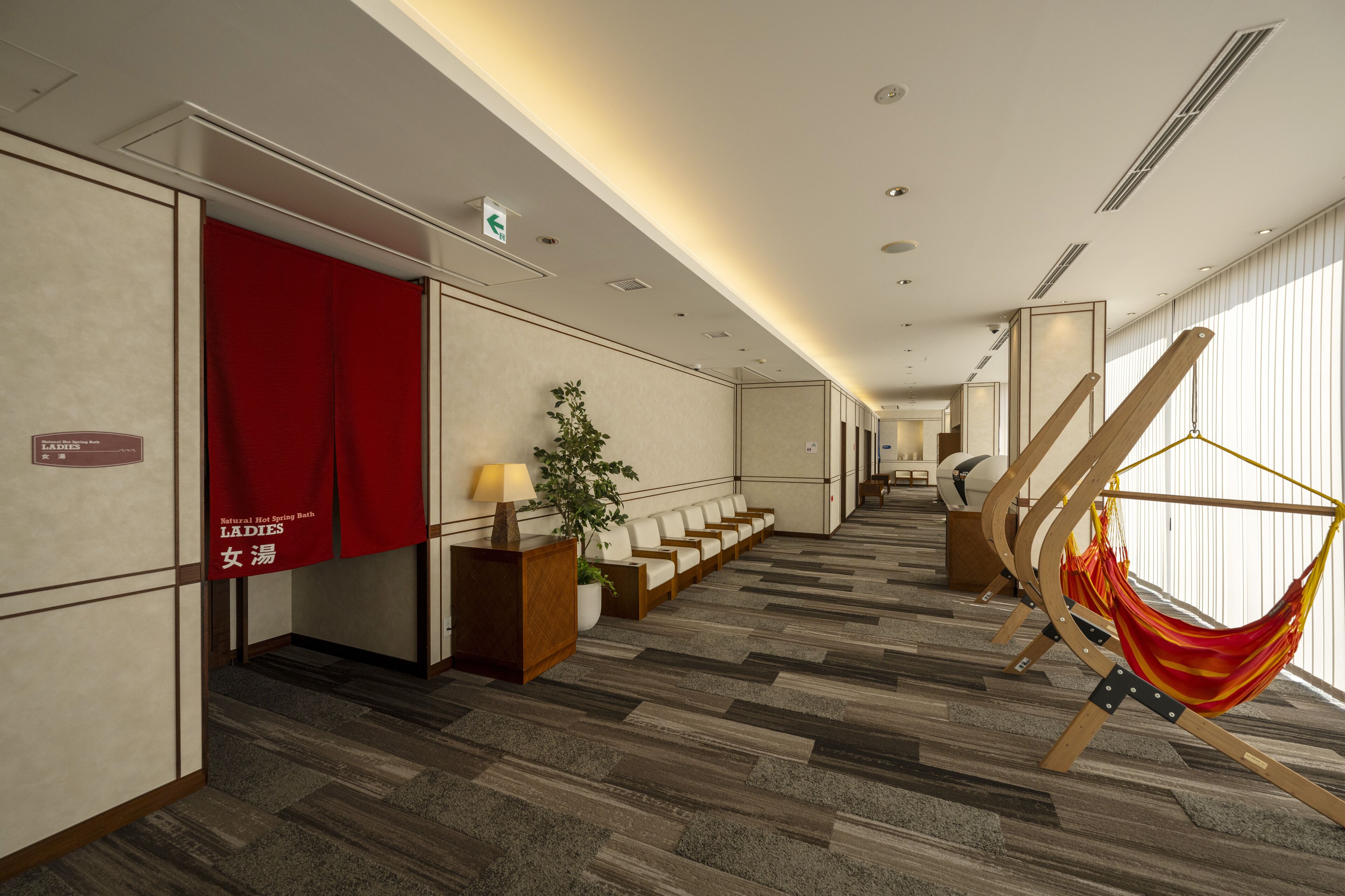 A hotel lobby with a red curtain, a reception desk, a plant, and a hammock.