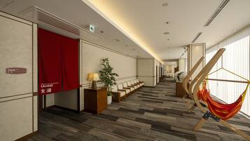 A hotel lobby with a red curtain, a reception desk, a plant, and a hammock.