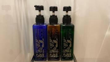 Tres botellas de jabón corporal y acondicionador sobre una repisa.