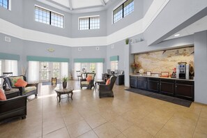 A spacious lobby with high ceilings, large windows, and a reception desk with a world map backdrop.