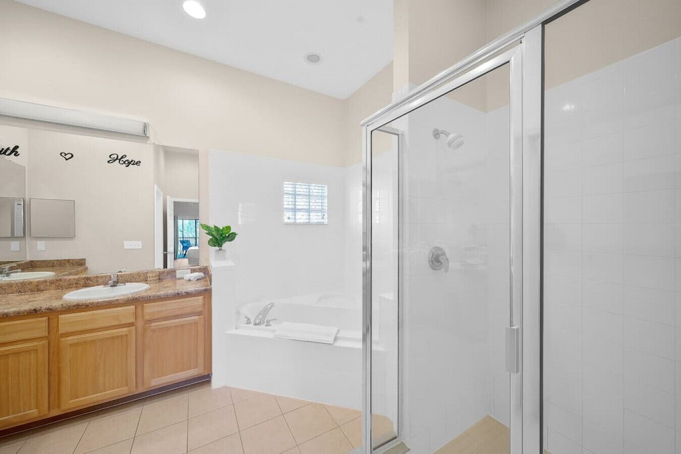 Un bagno moderno con cabina doccia in vetro, vasca da bagno e un mobile lavabo con specchio e due lavabi.