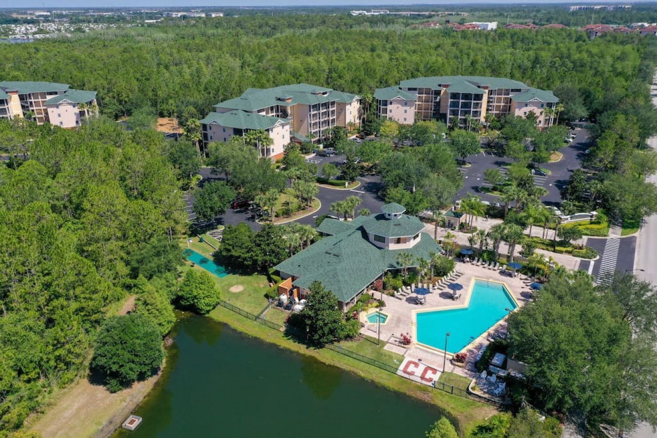 A resort with multiple buildings, a swimming pool, and a lake.