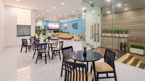 A modern hotel lobby with a seating area, a reception desk, and a glass partition. - The Home Hotel & Apartment (Da Nang)