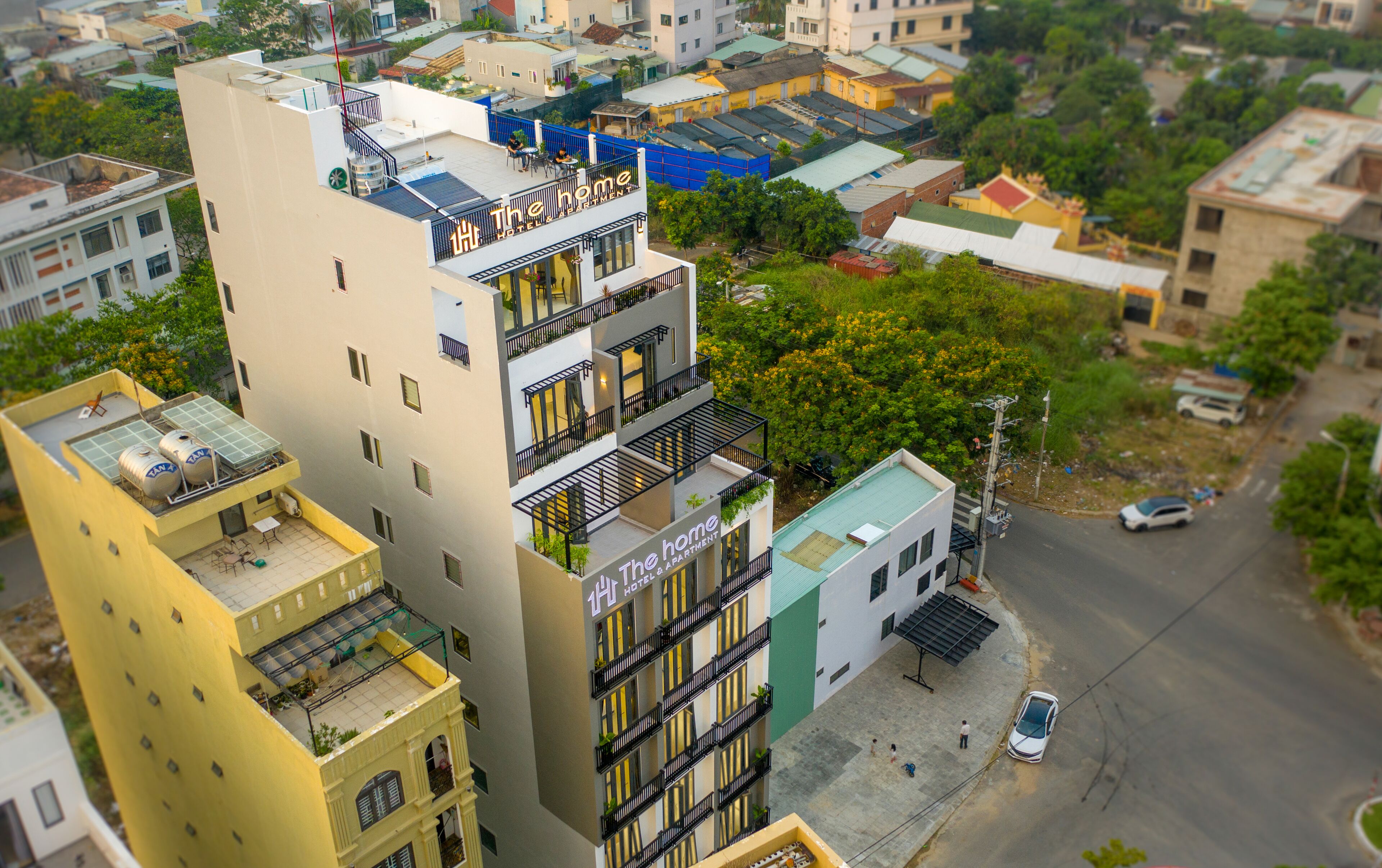A multi-story hotel with balconies, a rooftop terrace, and a street view.