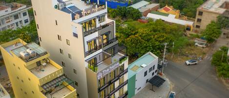 A multi-story hotel with balconies, a rooftop terrace, and a street view.