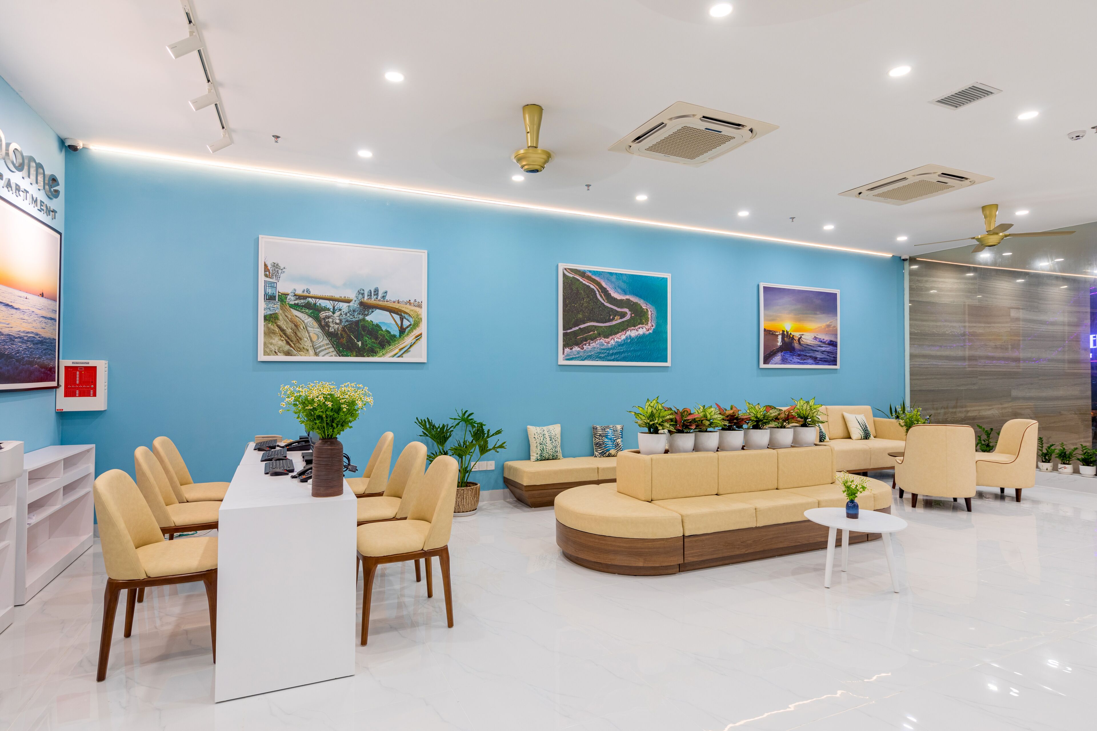 Uma área de recepção moderna com parede azul, balcão de atendimento, assentos bege e três quadros emoldurados.