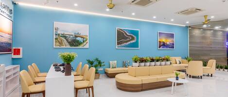 A modern reception area with a blue wall, a reception desk, beige seating, and three framed pictures.