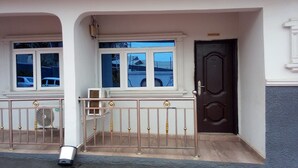 Een huis met twee verdiepingen, een receptie, een donkerbruine deur en een witte balkonbalustrade.