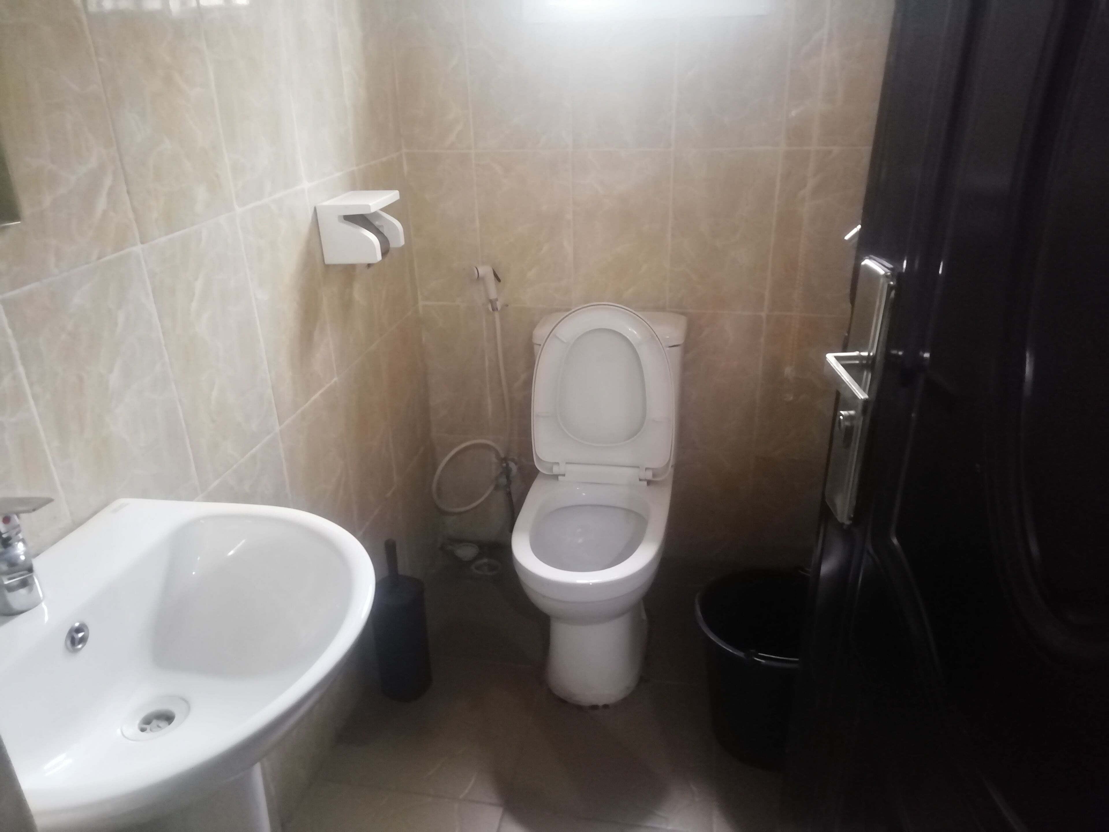 Un baño con inodoro, lavamanos y un cubo de basura.