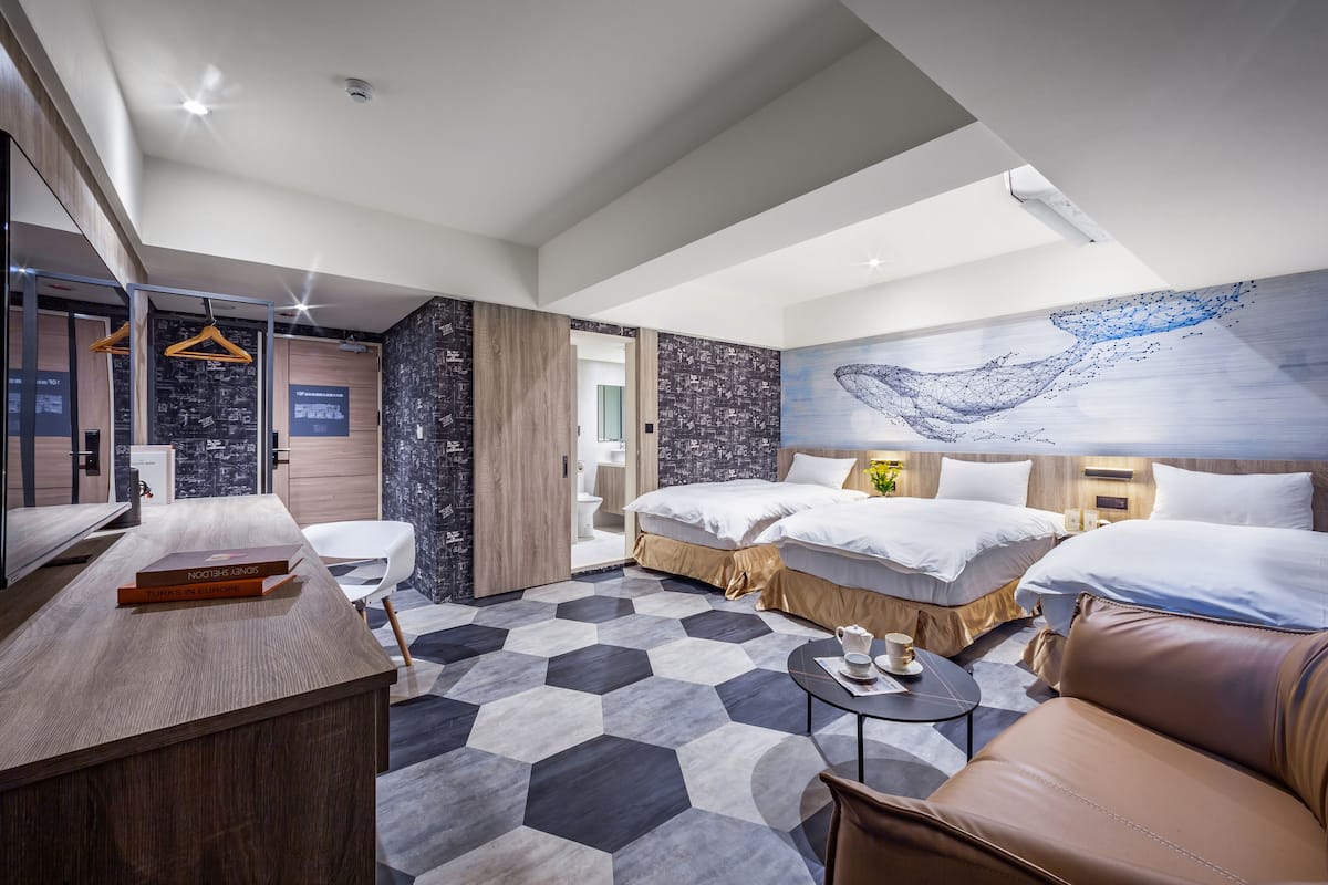 A modern hotel room with a large bed, a desk, and a seating area.