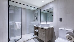 A modern bathroom with a glass shower enclosure, a sink with a mirror above it, and a toilet with a toilet paper holder. - modayhotel (Taichung)