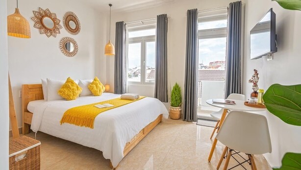 Ein Hotelzimmer mit Bett, Schreibtisch, Fernseher und großen Fenstern.