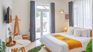 Ein modernes Hotelzimmer mit einem großen Bett, einem Schreibtisch und einem Balkon mit Vorhängen.