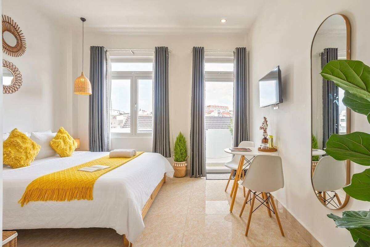 A hotel room with a bed, a dining table, chairs, a TV, and a large mirror.