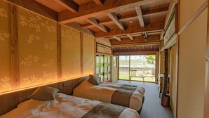 Een hotelkamer met twee bedden, houten balken in het plafond en uitzicht op het omliggende landschap.