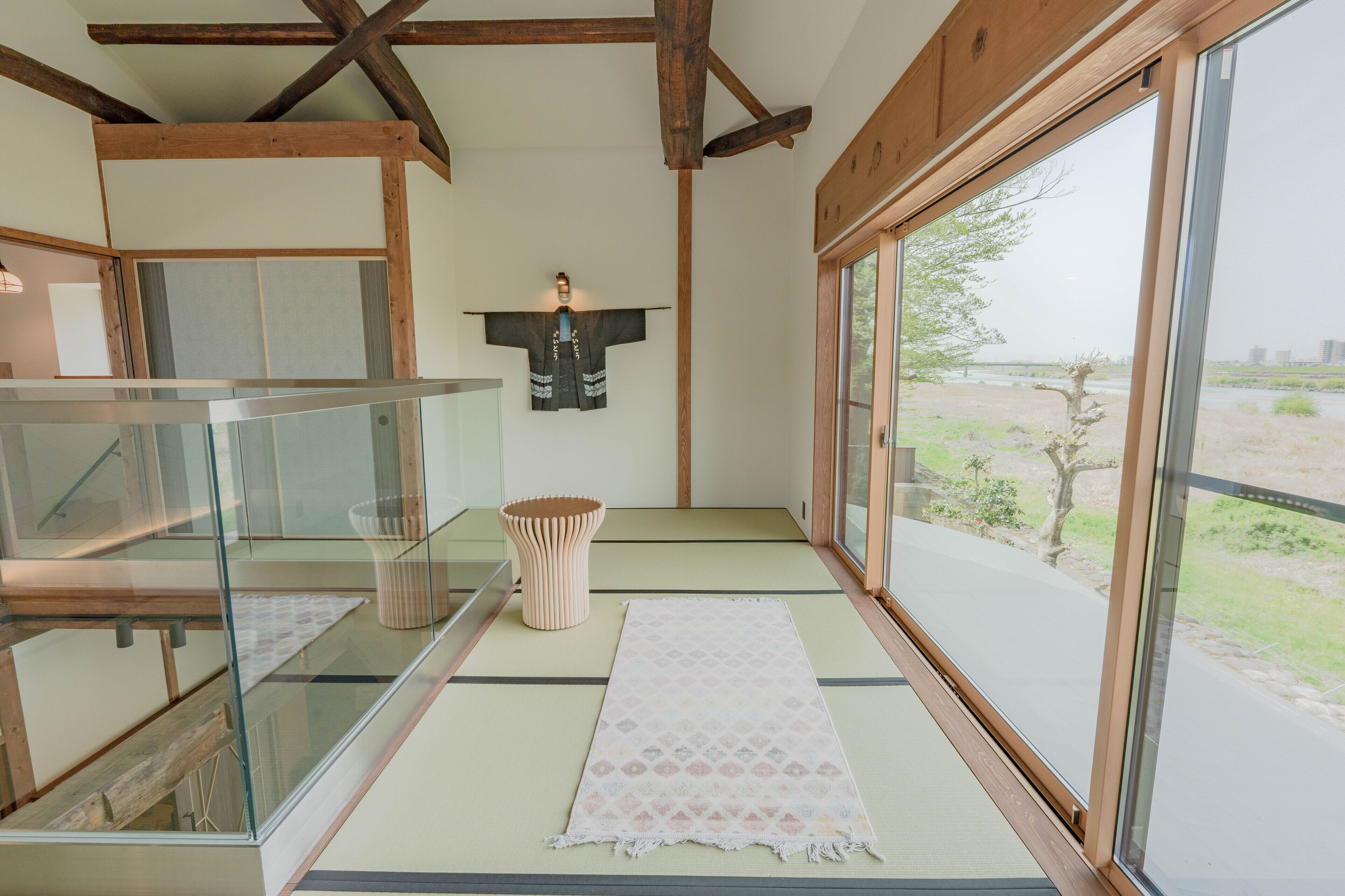 Um quarto japonês tradicional com piso de tatame, um painel shoji e vista para o exterior.