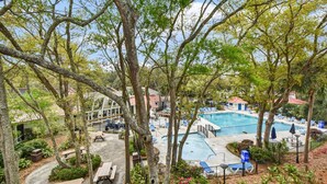 A pool area with lounge chairs and a small building in the background. - Villa 260 Getty Building (Jekyll Island)