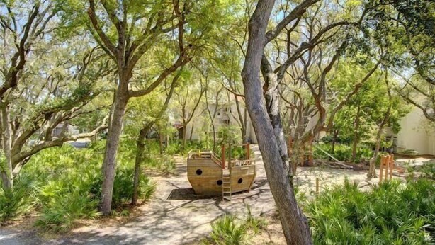 A serene garden with a wooden boat structure, surrounded by lush greenery and trees. - Villa 260 Getty Building (Jekyll Island)