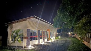 Un bâtiment moderne doté d’un comptoir d’accueil, de portes vitrées et d’un chemin menant à une entrée sécurisée par un portail.