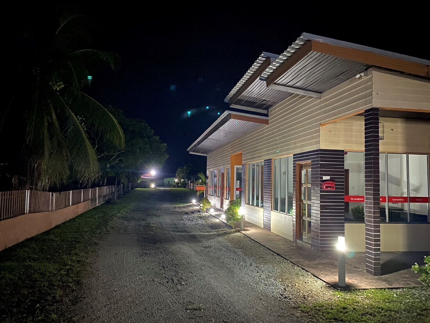 A modern building with a gravel driveway and a fence.