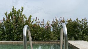 Une piscine dotée de rampes métalliques et d’une terrasse carrelée.