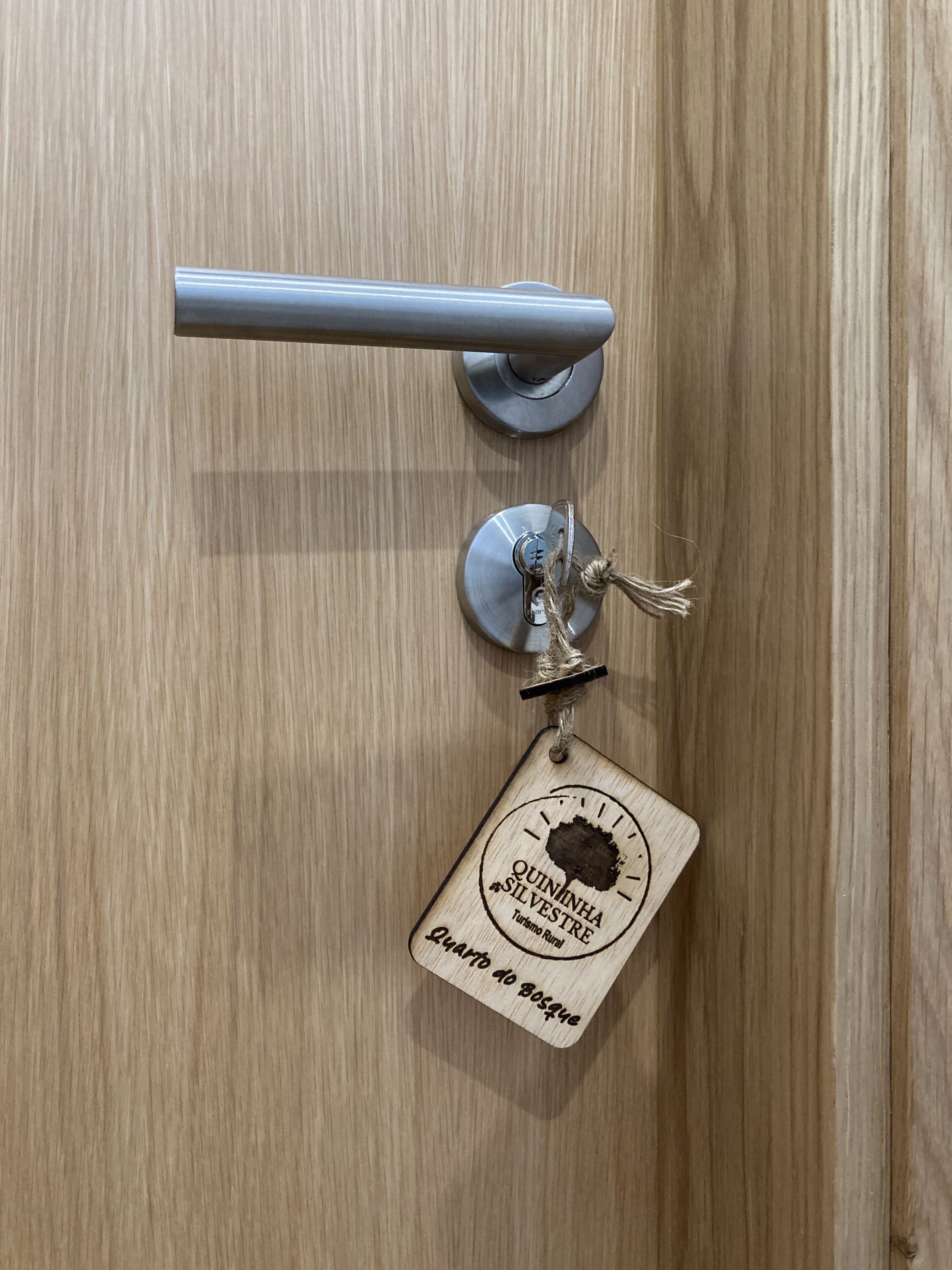 A wooden door with a keyhole and a keychain with a wooden plaque.