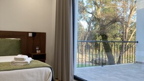 Une chambre moderne avec une grande fenêtre, une tête de lit en bois et un tapis vert.